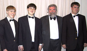 The four band members in formal black concert dress with bow ties